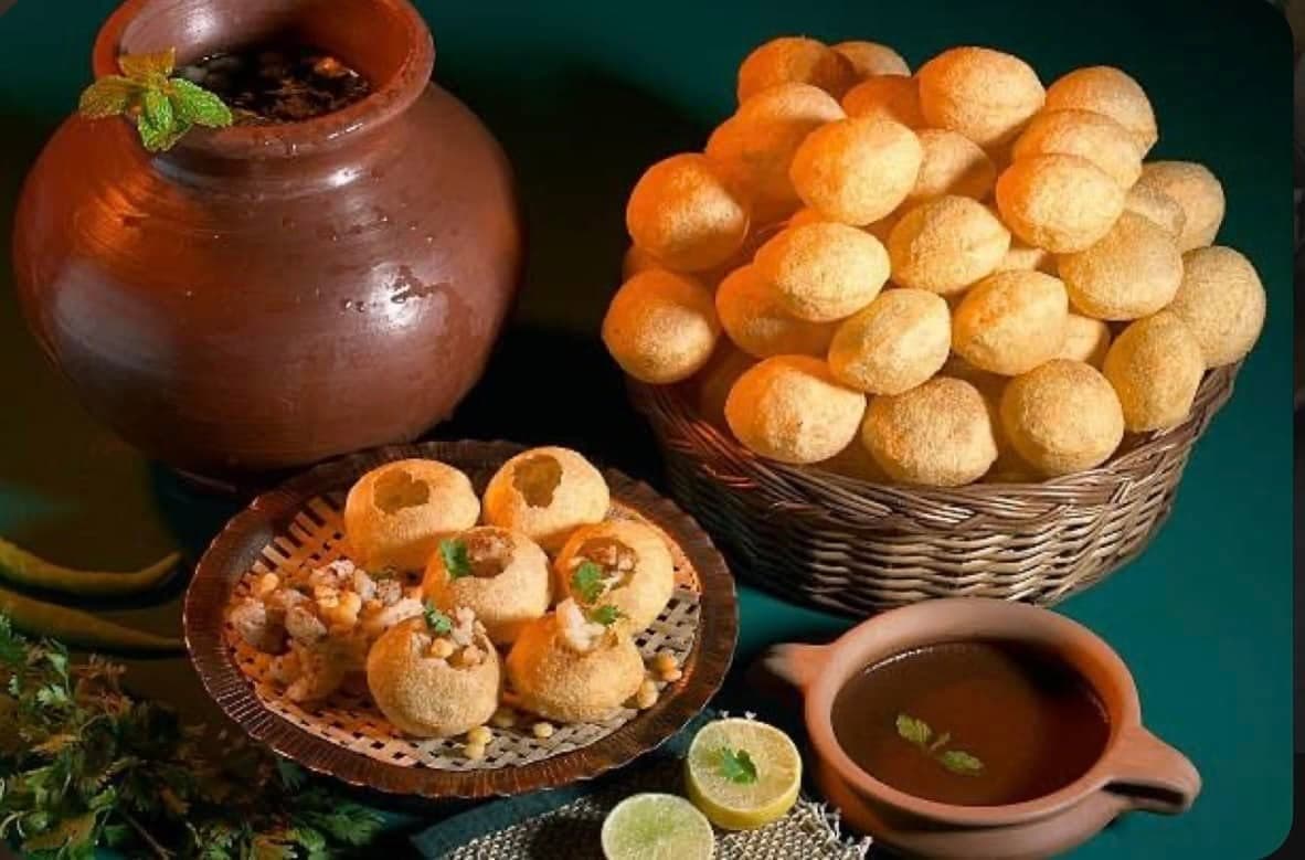 Pani puri โ crispy puris filled with spiced potato and chickpeas, served with tangy mint water